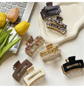 Flat lay of square hair claws in plaid and marble patterns on a decorative tray