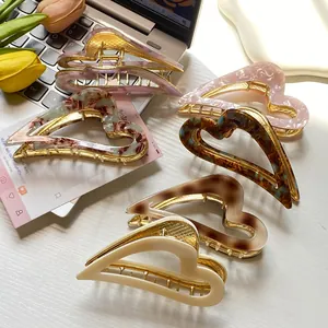 Elegant heart-shaped hollow metal hair claws in various acetate colors on desk