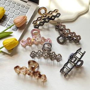 Elegant hollow floral hair claw clips set in various colors on a modern desk setup