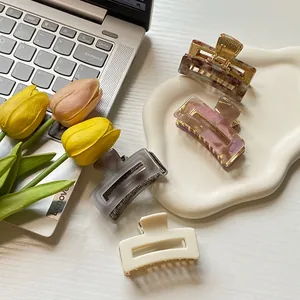 Set of four small square hair claws in marble acrylic and matte finishes on a desk