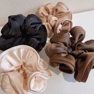 Détail de quatre chouchous en satin de couleurs noir, champagne, beige et marron foncé