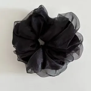 Detail of a large black organza scrunchie with elegant layered tulle folds and texture