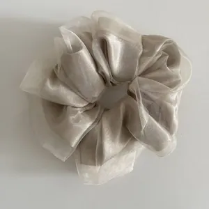 Detail of champagne gold satin scrunchie with layered translucent organza texture