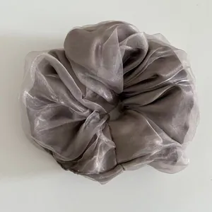 Detail view of a silver-grey organza mesh scrunchie with soft pleats and a silky sheen finish
