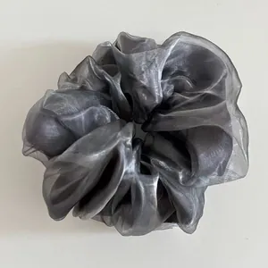 Detail of silver grey organza hair scrunchie with shimmering texture and soft pleats
