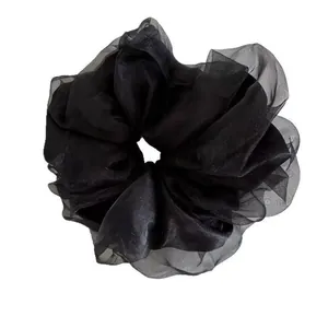 Close-up of black oversized organza scrunchie with layered pleated fabric design