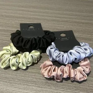 Set di quattro elastici per capelli in raso colori pastello su carta espositiva