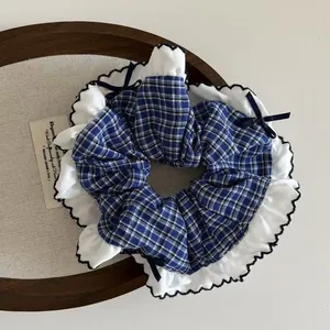 Close-up of navy blue plaid scrunchie with white lace edges and a delicate ribbon bow