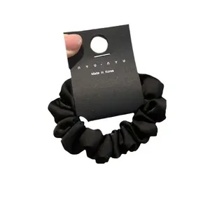 Dettaglio di un elastico in raso nero con etichetta nyu nyu su uno sfondo bianco