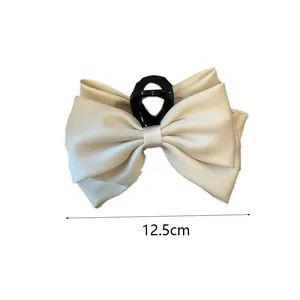 Detailed view of cream satin bow hair claw clip measuring 12.5cm width with black plastic base