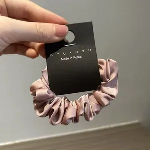 Dettaglio dell'elastico in raso rosa con trama setosa e carta del marchio nyunyu