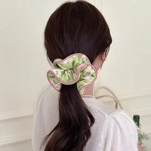 Floral oversized hair scrunchie with pink trim shown on a low ponytail hairstyle