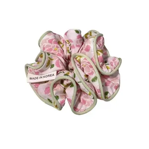 Detailed macro view of pink floral scrunchie with green trim and Made in Korea tag