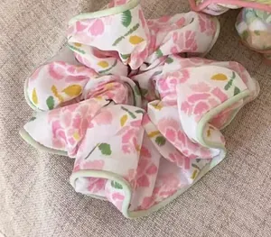 Detailed close-up of pink floral pattern scrunchie with green fabric edge trim