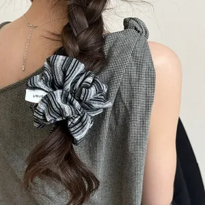 Chouchou en tissu à rayures noires et blanches porté sur une coiffure tressée