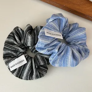 Gros plan de chouchous en tissu rayé bleu et noir avec motifs de vagues et étiquettes