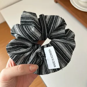 Détail d'un grand chouchou en tissu à rayures noires et blanches avec texture tissée