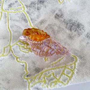 Seashell-shaped acetate hair claw clip with orange and purple marble textures