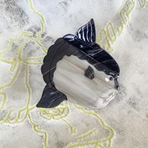 Detail of mola mola hair clip with marble textured acetate and engraved fin patterns