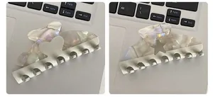 Detail of cream marble acetate hair claws with heart and star patterns on a keyboard