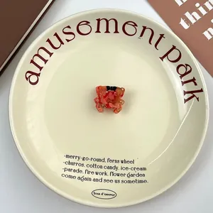 Close-up of a cute orange acetate crab hair claw clip on an elegant ceramic plate