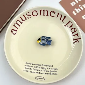 Blue fish-shaped acetate hair claw clip displayed on a minimalist ceramic plate decor