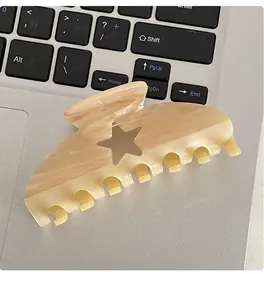 Close-up of a marble acetate hair claw clip with star cutout detail on a laptop keyboard