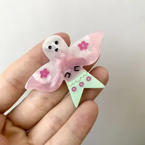 Vue détaillée de la pince à cheveux en acétate avec des ailes roses et un motif fantôme