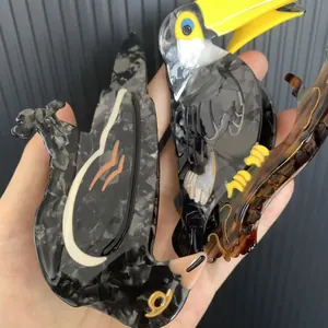 Toucan-shaped acetate hair claw with grey marble texture and vibrant yellow beak detail