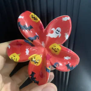Détail d'une pince à cheveux fleur rouge avec motifs de citrouille et fantôme d'Halloween