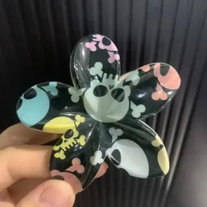 Détail de la pince à cheveux en forme de fleur avec motif crânes et os colorés