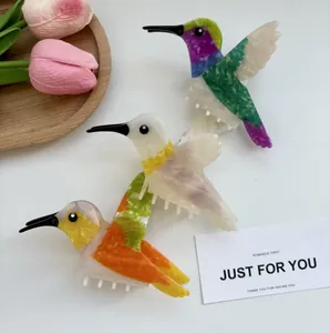 Pinces à cheveux colibri en acétate coloré aux motifs variés sur fond blanc élégant