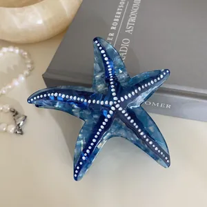 Gros plan d'une pince à cheveux étoile de mer bleue avec texture marbrée et perles