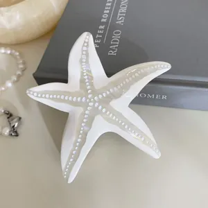Détail de la pince à cheveux étoile de mer en acétate blanc nacré avec texture à pois