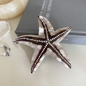 Détail macro d'une pince à cheveux étoile de mer en acétate avec finition nacrée et points