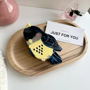 Détail de la pince à cheveux en acétate en forme d'oiseau avec motif perroquet bleu