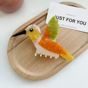 Détail d'une pince à cheveux colibri colorée avec textures marbrées en acétate