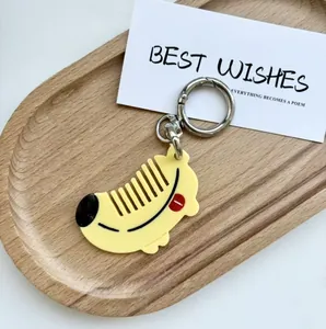 Detail of yellow crescent moon animal keychain with silver metal clasp on wooden tray