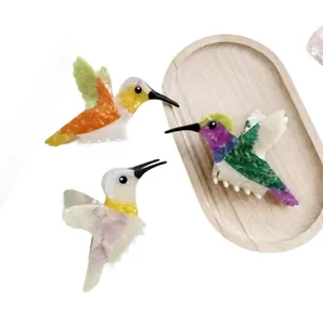 Trois pinces à cheveux colibri en acétate avec motifs colorés sur un fond blanc épuré