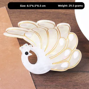 Detailed view of white peacock hair claw clip with rhinestones on a wooden background