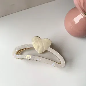 Glossy pearlescent half-round hair claw clip with cream heart detail and gold teeth