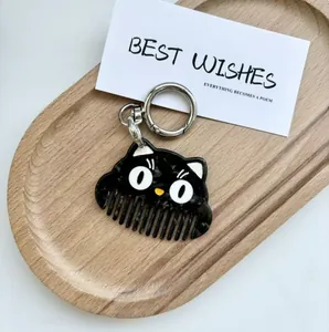 Detail of creative black cat keychain comb with polished finish and metal lobster clasp