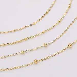 Detail of layered gold-plated copper chains featuring various sizes of metal beads
