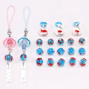Vue détaillée de perles en verre fait main avec motifs de poissons rouges et breloques
