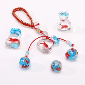 Gros plan d'un pendentif poisson rouge en verre avec cordon rouge et breloques coeur