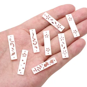 Primer plano de colgantes calados de acetato blanco para creación de joyas DIY