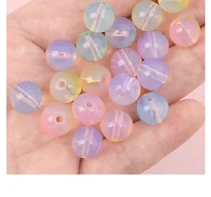 Close-up of iridescent colorful round glass beads for DIY jewelry making in a hand