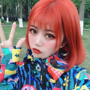Short straight bright orange bob wig with bangs worn with colorful floral print jacket