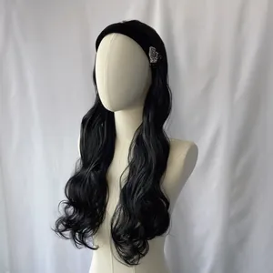 Long black wavy synthetic wig with headband and vintage jewel brooch on a white mannequin