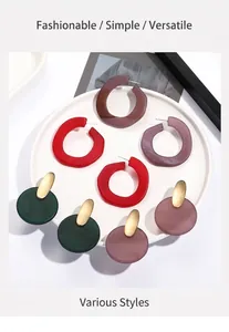 Detail view of colorful C-shaped acrylic earrings and resin studs on a white round tray
